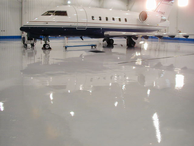 corporate jet with epoxy flooring system in hanger, non yellowing formula, UV-stable colors.