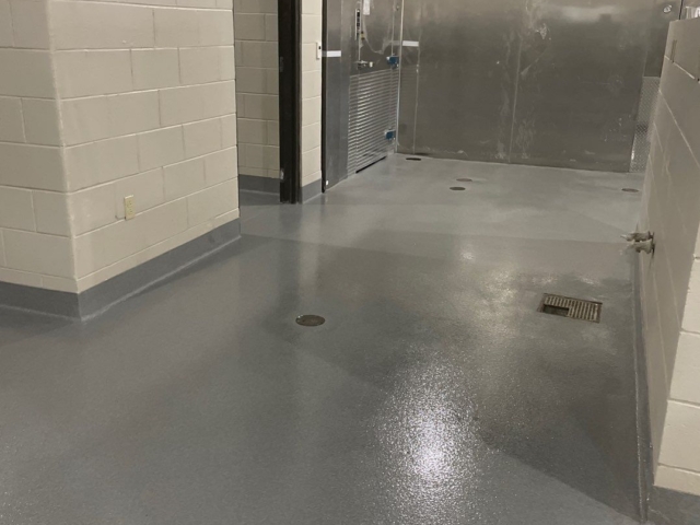 Industrial Applications, Inc. installed decorative quartz flooring for new school with two coats of mid coat with colored quartz aggregate near walk-in refrigerator and freezer.