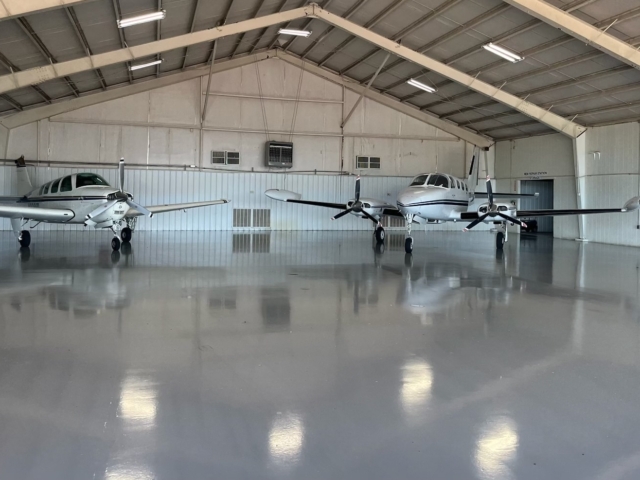 sleek, easy to clean urethane coatings on airplane hanger floor - photos also shows two private planes in the hanger