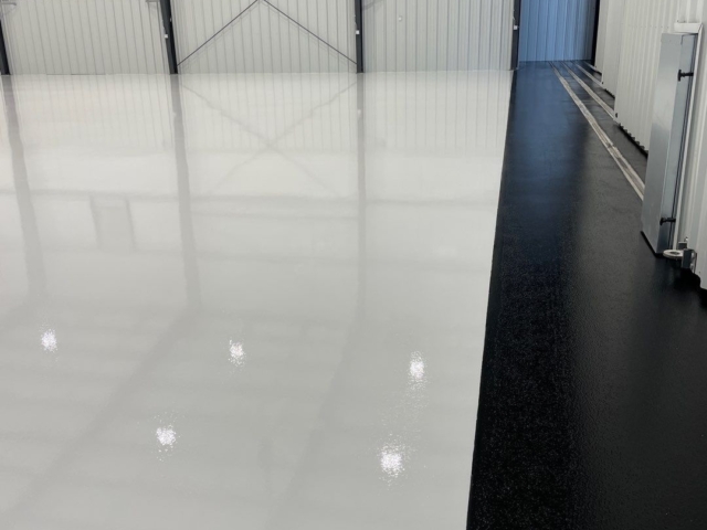 Transformed airplane hangar with a durable and stunning epoxy and urethane coated floors with white and black epoxy