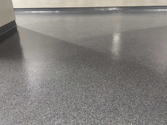 Industrial Applications, Inc. recently installed a colored troweled quartz flooring system throughout the hallways, restrooms, and commercial kitchen of a busy high school.